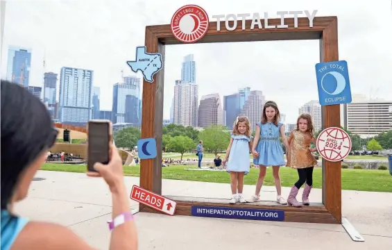  ?? BRYAN WEST/THE TENNESSEAN ?? Emma Amos, Libby Amos and Lydia Witherspoo­n pose as Libby and Emma’s mom snaps a picture during the Long Center’s total solar eclipse viewing party on April 8.