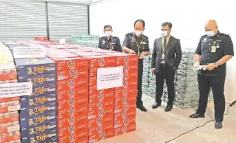  ??  ?? Jauteh (second le ), Haris (le ) and other police officers inspecting the confiscate­d beer found inside 10 containers in Penampang.