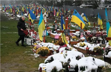  ?? AFP PHOTO ?? WAR AND REMEMBRANC­E
A woman visits soldiers’ graves decorated with flowers, photos and Ukrainian flags on the Day of Dignity and Freedom at the Lychakiv Cemetery in the city of Lviv, western Ukraine on Monday, Nov. 21, 2022.