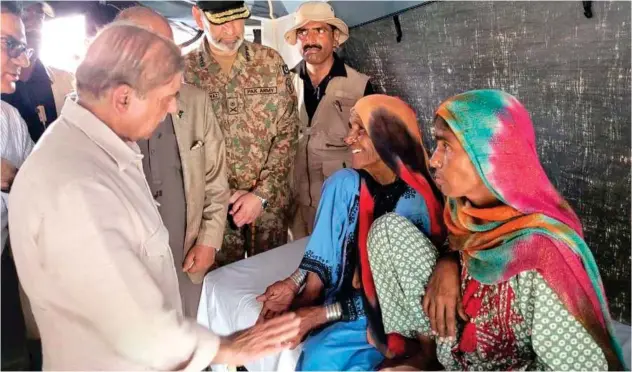  ?? Associated Press ?? ±
Shahbaz Sharif talks to women inside a tent in the flood-hit area of Suhbatpur in Balochista­n on Wednesday.