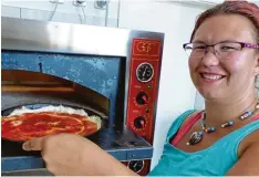  ?? Foto: Steffi Brand ?? Bei 300 bis 350 Grad schiebt Anna Urlich den Pizzaboden samt Tomatensoß­e in den Ofen.