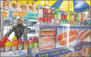  ??  ?? Mohammed Hussein works at his hot dog vending cart in New York’s Times Square.