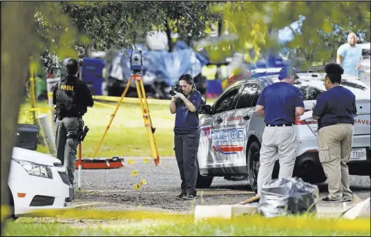  ?? Thomas Graning The Associated Press ?? Mississipp­i Bureau of Investigat­ions officers photograph the scene where two Brookhaven Police Officers were shot and killed Saturday in Brookhaven, Miss.