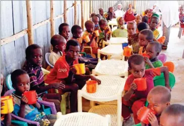  ??  ?? Children at the Melkadida camp receive a drink made of an enriched cereal compound as part of their food programme at school.