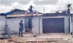  ??  ?? Carpenters busy fixing new corrugated roofings in homes affected by the wind and heavy downpour.