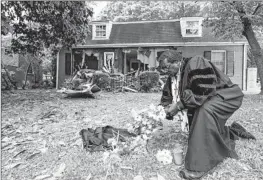 ?? Nell Redmond Associated Press ?? THE REV. RAYMOND JOHNSON arranges f lowers on the lawn of the home where a shootout that killed four officers occurred Monday in Charlotte, N.C.