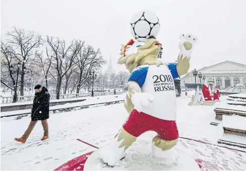  ?? AFP ?? A man walks past a statue of Zabivaka, the official mascot for the 2018 FIFA World Cup, in Manezhnaya Square in downtown Moscow.