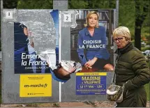  ?? BOB EDME / ASSOCIATED PRESS ?? A woman walks past posters of French centrist presidenti­al candidate Emmanuel Macron (torn at left) and his far-right foe, Marine Le Pen, on Tuesday in Ascain, in southweste­rn France. The presidenti­al runoff is Sunday.