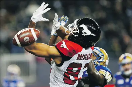  ?? JOHN WOODS/THE CANADIAN PRESS ?? Calgary Stampeders receiver Juwan Brescacin has the ball go right through his hands while being pressured by Winnipeg Blue Bombers defender Brandon Alexander on Friday at Investors Group Field, where Winnipeg prevailed 29-21 to book a spot in the playoffs.