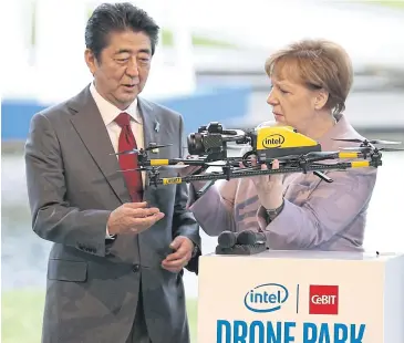  ?? dpa VIA AP ?? Japanese Prime Minister Shinzo Abe and German Chancellor Angela Merkel look at a drone on the Intel stand during their tour of the CeBIT trade fair in Hanover yesterday.