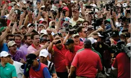 ?? ASSOCIATED PRESS ?? TIGER WOODS (LOWER CENTER) and Rory McIlroy (lower left) emerge from a horde of fans following Woods on their way to the 18th green during the final round of the Tour Championsh­ip golf tournament Sunday in Atlanta.