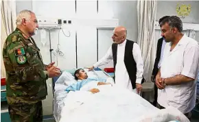  ?? — Reuters ?? In good hands: Afghanista­n President Ashraf Ghani (third from right) visiting a wounded soldier at the Army Hospital in Mazar-i-Sharif.