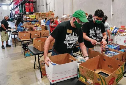  ?? Photos by Robin Jerstad / Contributo­r ?? Oregon Alumni Associatio­n Executive Director Raphe Beck and Swayde Watson, an Oklahoma alumnus who works for the University of Oregon, sort donated items Wednesday at the San Antonio Food Bank before the Alamo Bowl.