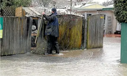  ?? MARTIN DE RUYTER/STUFF ?? Steve Holloway rushes to shore up a fence at his flooded property at Cooks Corner, near the Riuwaka River, during the heavy rain and strong winds that battered Nelson and Tasman yesterday.