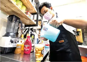  ?? — Bernama photo ?? Wan Mohd Azizul Solehin prepares drink for a customer at his cafe.