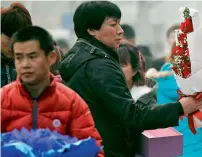  ?? AP ?? A man looks at Valentine’s Day roses at the flower market in Beijing, on Tuesday. Valentine’s Day is not a tradition in China but is becoming popular as Chinese adopt Western customs, encouraged by retailers who see them as a way of boosting sales. —