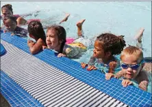  ?? Katharine Lotze/The Signal ?? Young swimmers practice kicking while grabbing the side of the pool during the World’s Largest Swimming Lesson at Santa Clarita Aquatic Center.