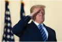  ?? Associated Press ?? ■ President Donald Trump salutes Monday as he stands on the Blue Room Balcony upon returning to the White House after leaving Walter Reed National Military Medical Center in Bethesda, Md.