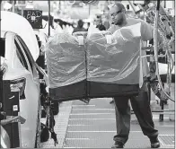  ?? AP file photo ?? An assembly line worker uses a lift to move a back seat into a new Nissan Altima sedan at the Nissan Canton Vehicle Assembly Plant in Canton, Miss.