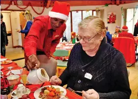  ??  ?? Tucking in: Red Cross volunteer Adam Abillahi pours a tasty helping of gravy for Terry Clarke, the uncle of TV host Ant McPartlin