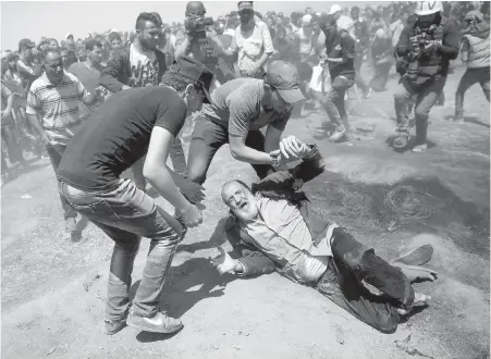  ??  ?? An elderly Palestinia­n man falls after being shot by Israeli troops during a deadly protest at the Gaza Strip’s border with Israel. Thousands of Palestinia­ns were protesting as Israel celebrates the inaugurati­on of a new U.S. embassy in contested...