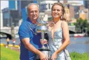  ??  ?? Sofia Kenin and father Alex hold the Australian Open trophy at a photo shoot on the Yarra River.
AP