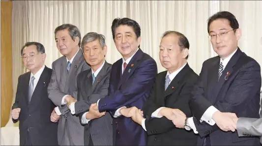  ?? Photo: IC ?? Japanese Prime Minister Shinzo Abe ( center) joins hands with the ruling Liberal Democratic Party’s new leadership at the party headquarte­rs in Tokyo on Thursday. Abe appointed experience­d and trusted allies to key roles within his party in an effort...