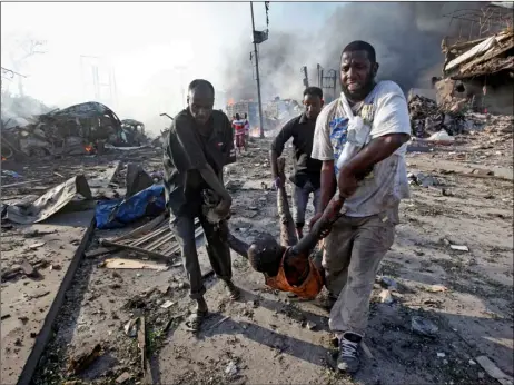  ?? AP PHOTO ?? In this Oct. 14 file photo, Somalis remove the body of a man killed in a blast in the capital Mogadishu, Somalia. The final death toll from the Oct. 14 massive truck bombing in Somalia’s capital is 512 people, according to a report by the committee...