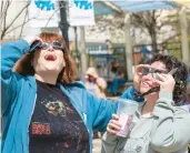  ?? ?? Jamie Watkins, left, and Joanna Mangano of Bath watch the solar eclipse Monday at the Promenade Shops.