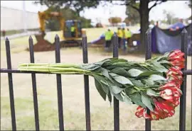  ?? Mike Simons Tulsa World ?? FLOWERS HANG on a fence as crews search for remains at Oaklawn Cemetery in Tulsa, Okla. The 1921 racial attack left about 300 people dead and 800 wounded.