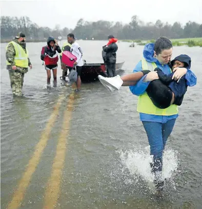  ?? AFP / CHIP SOMODEVILL­A ?? ▶▶ Voluntario­s ayudan a tres niños cuya casa estaba inundada, ayer.