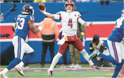  ?? AL BELLO/GETTY IMAGES ?? Washington Commanders quarterbac­k Taylor Heinicke throws a pass as New York Giants linebacker Oshane Ximines closes in during a Dec. 4 game. Both players are former Old Dominion stars.