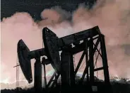  ?? David McNew / Getty Images ?? Pump jacks stand near a wildfire in Somis, Calif. Congress is being urged to heed climate warnings.