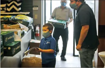  ?? (AP PHOTO/LM OTERO, FILE) ?? In this April 22, 2020file photo, amid concerns of the spread of COVID-19, kindergart­ner Eli Schweig, 6, helps his father Brad Schweig, right, and grandfathe­r David Schweig unload products as they prepare their family owned retail store Sunnyland Outdoor Living for a limited re-opening in Dallas. As small and midsize businesses rehire laid-off employees and get back to work, owners are making substantia­l changes to their operations to protect staffers from the coronaviru­s.