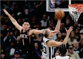  ?? ASSOCIATED PRESS ?? shoots past Phoenix Suns guard Devin Booker (1) during the second half Friday in San Antonio. San Antonio won 103-89.