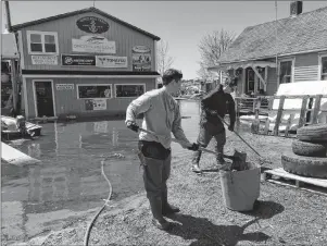  ?? AP PHOTO ?? Danielle Ring, 23, (left) and her sister Rebecca, 20, shovel debris out of water that flooded the front driveway of their father’s boat service business in Saint John, N.B., on Tuesday