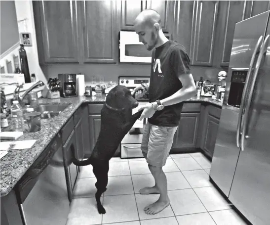  ?? Associated Press ?? Ian Supra, 19, dances in the kitchen with his therapy dog Penelope as he feels good enough to cook pasta on April 16, 2015, at his Orlando, Fla., home. “She helped me so much in the past few months, she’s been a blessing,” he said.