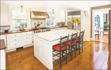  ?? Photos by Michelle& Company ?? Above: The renovated gourmet kitchen features sleek wood countertop­s and an island and breakfast bar topped in Carrara marble. Below left: The terrace at 43 Red Coat Road in Westport extends to the heated pool and spa. Below right: The living room is highlighte­d by tall windows and a wood- burning fireplace.