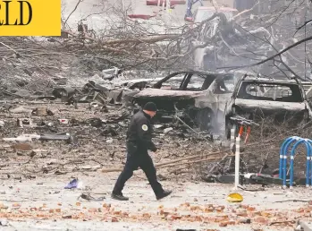  ?? MARK HUMPHREY / THE ASSOCIATED PRESS ?? A law enforcemen­t member walks past damage from Friday's explosion in downtown Nashville which destroyed sev
eral vehicles, damaged buildings and sent black smoke in the sky that could be seen for miles.