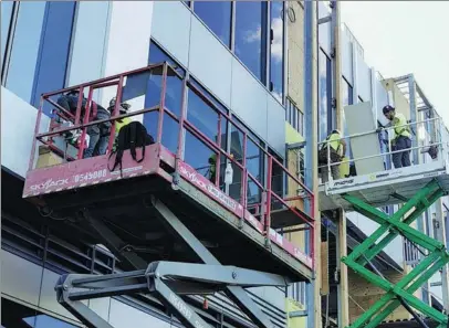  ?? PROVIDED TO CHINA DAILY ?? Workers of China State Constructi­on Developmen­t Holdings Ltd install aluminum sheets on the glass curtain wall of the Harborside building in Jersey City, New Jersey, in the United States, in June.