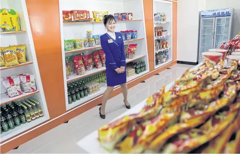  ??  ?? A sales clerk welcomes customers in a store in a new residentia­l complex in Ryomyong street in Pyongyang, North Korea.