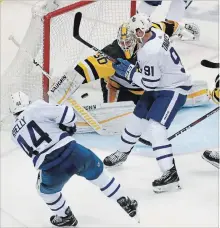  ?? GENE J. PUSKAR THE ASSOCIATED PRESS ?? Toronto Maple Leafs defenceman Morgan Rielly, left, gets the puck past Penguins goaltender Matt Murray for his second goal of the game in the third period in Pittsburgh on Saturday. The Maple Leafs won, 5-0.