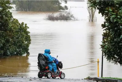  ?? The Associated Press ?? Q A woman looks over the flooded farmland at Richmond on the outskirts of Sydney, Australia, on Monday. More than 30,000 residents of Sydney and its surrounds have been told to evacuate or prepare to abandon their homes on Monday as Australia’s largest city braces for what could be its worst flooding in 18 months.