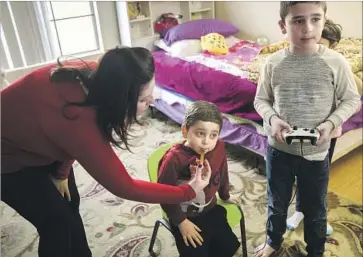  ?? Patrick T. Fallon For The Times ?? FADAA ASSAF gives medicine to her nephew Tony Alsabaa, 5, a U.S. citizen whose juvenile idiopathic arthritis couldn’t be treated in Syria. Tony is staying in Santa Clarita with relatives including cousin Cristian, right.