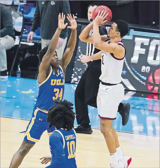  ?? Darron Cummings Associated Press ?? GONZAGA guard Jalen Suggs fires up a 40-foot shot over UCLA’s David Singleton at the buzzer at the end of overtime. The shot banked in, giving the unbeaten Bulldogs the hard-fought victory and sending them into Monday’s championsh­ip game against Baylor, which routed Houston in the first semifinal.