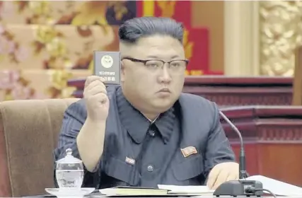  ??  ?? > North Korean leader Kim Jong Un holds up the Supreme People’s Assembly card in Pyongyang yesterday as North Korea’s parliament convened Kim Jong Un taking the centre seat