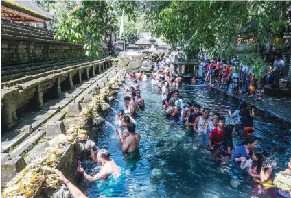  ??  ?? WORSHIPERS AT a temple purify themselves in a pool under ancient holy water spouts.