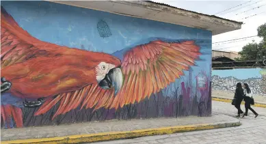  ?? Picture: AFP ?? Women walk near a mural of Cantarrana­s municipali­ty, west of Tegucigalp­a in Honduras .