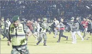  ?? (Pic: upi.com) ?? Soccer fans rush onto the field as military personnel try to stop them after a match at Kanjuruhan Stadium in Malang, East Java, Indonesia, on Saturday night.