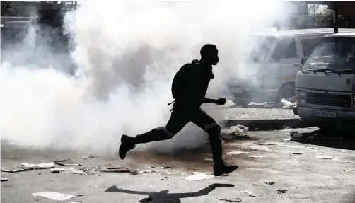  ?? | THEMBA HADEBE AP ?? A MAN runs away from tear gas after making off with goods from a store in Germiston, east of Johannesbu­rg, yesterday. Police earlier fired rubber bullets as they struggled to stop looters who targeted businesses as unrest broke out in several spots in the city.